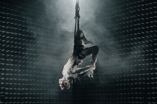 Photo of person hanging by one leg on rope