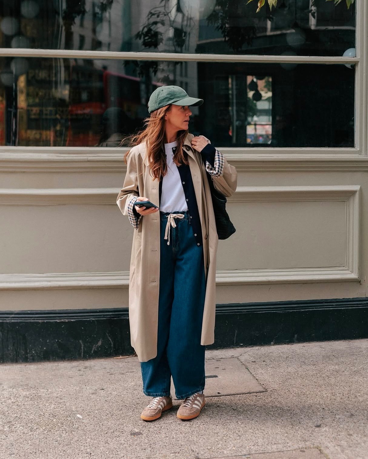 Fashion person Kim Turkington wears the drawstring jean trend. She pairs in with beige trainers, a white t-shirt black cardi and beige trench in a recent image from her Instagram.