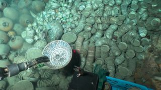 An underwater view of hundreds of artifacts, including pieces of pottery and ceramics. 