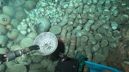 An underwater view of hundreds of artifacts, including pieces of pottery and ceramics.