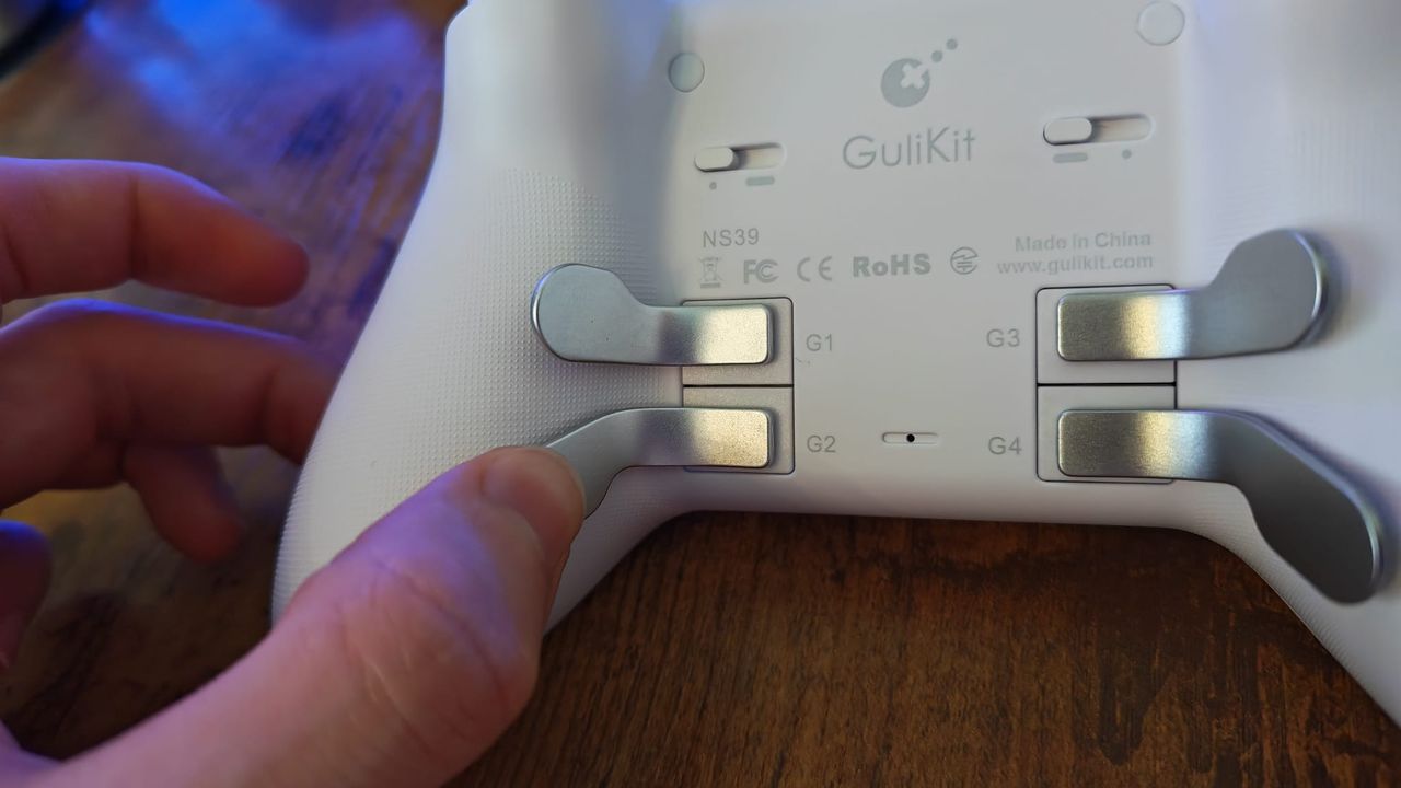 A reviewer pressing one of the back paddles on the Gulikit KK3 Max