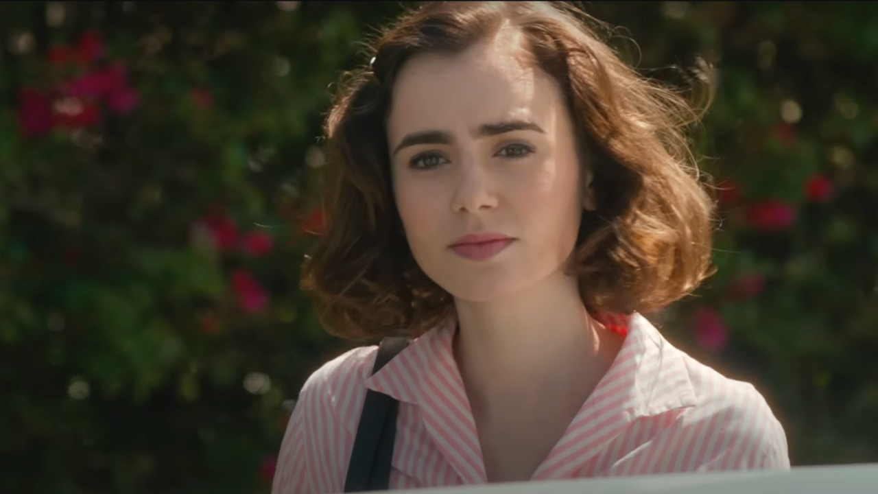 Lily Collins standing next to a car in a pink striped shirt in Rules Don't Apply.