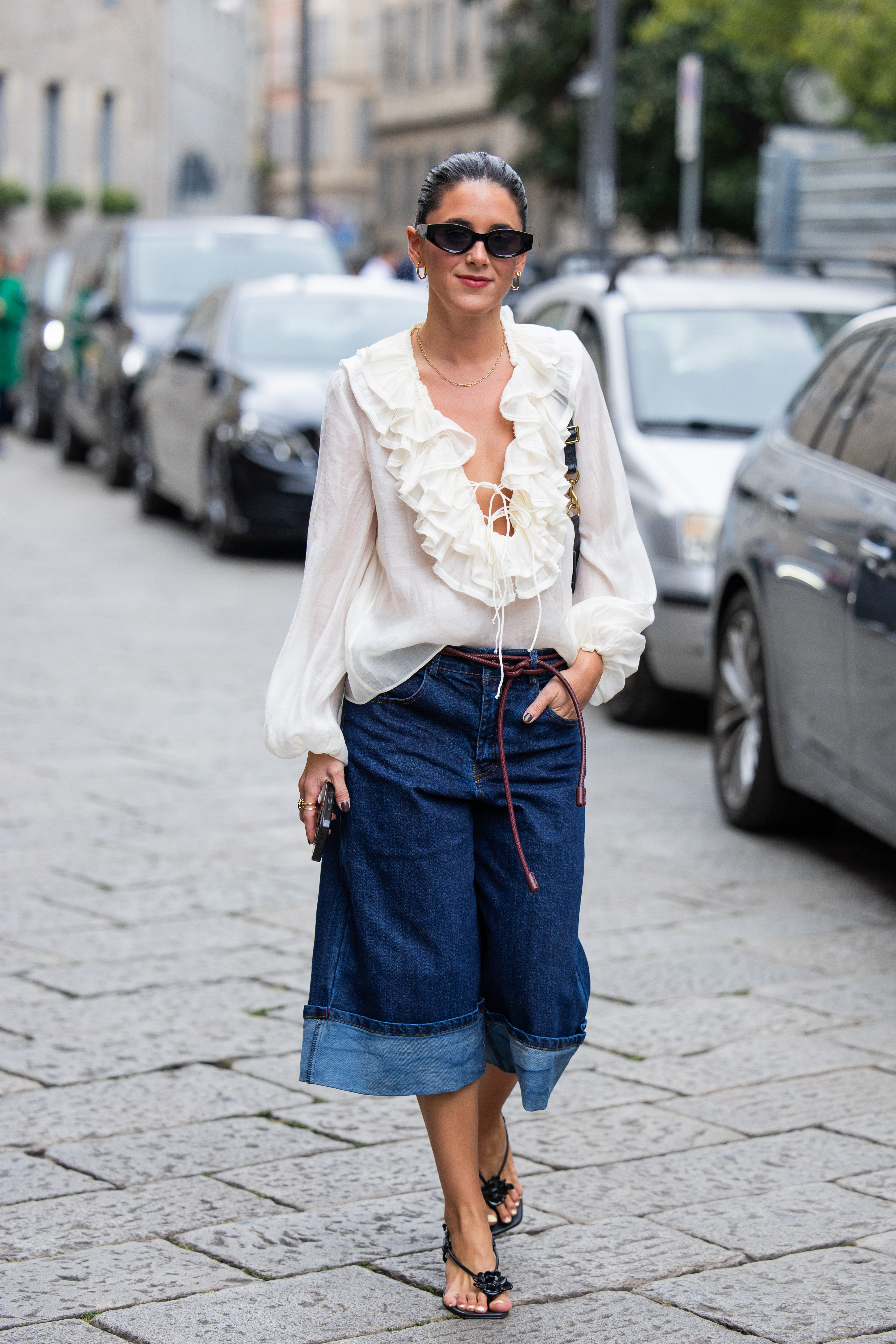 Influencer wears a boho blouse and jeans at Milan Fashion Week.