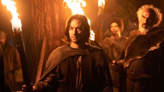 Isildur (Maxim Baldry) holds a burning torch in &quot;The Rings of Power&quot; season 2