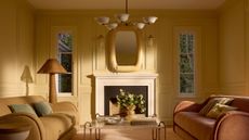 Butter yellow loving room featuring sculptural muted pastel furniture and a floral-inspired chandelier overhead