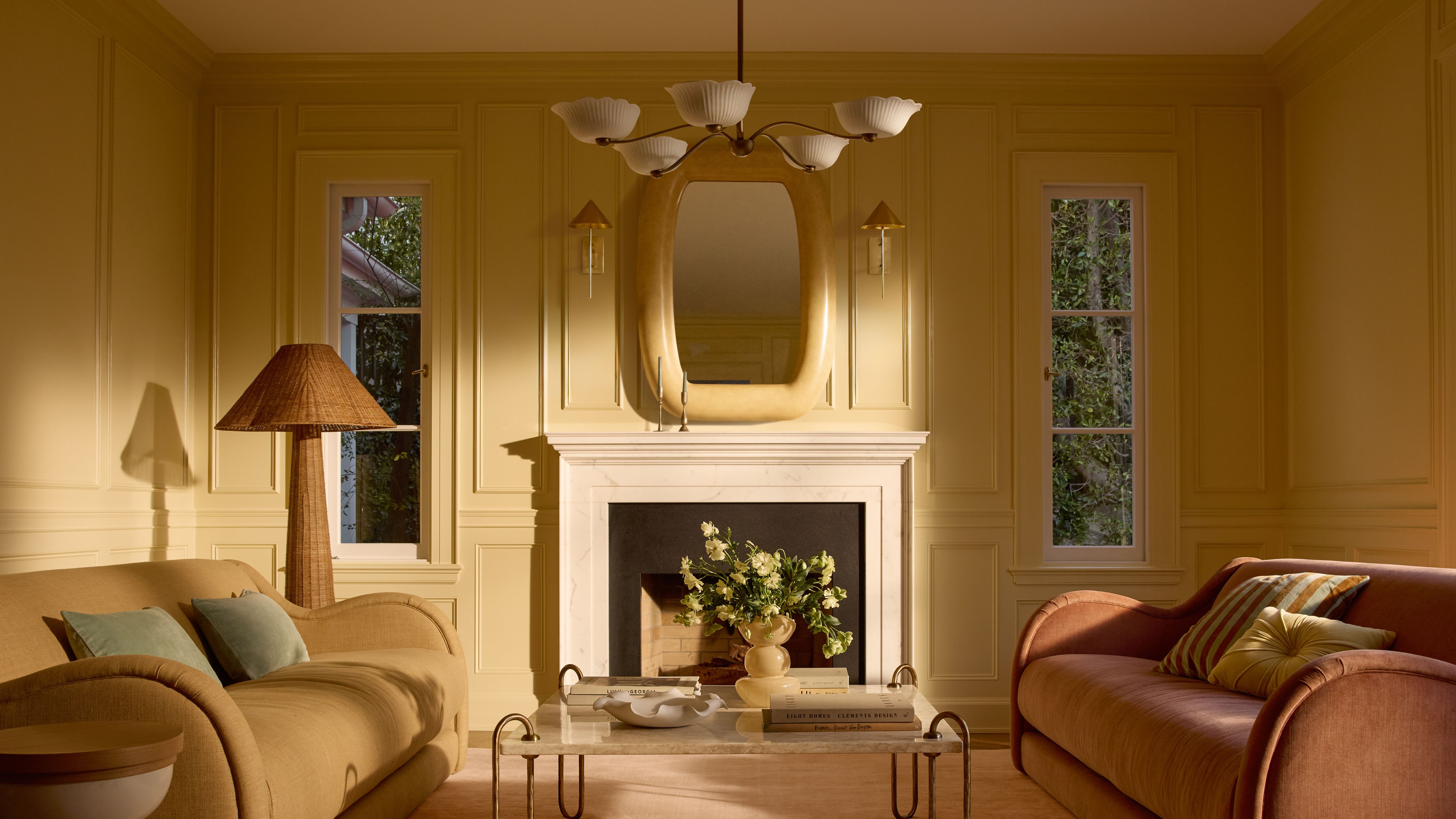 Butter yellow loving room featuring sculptural muted pastel furniture and a floral-inspired chandelier overhead