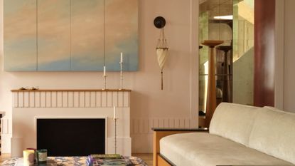 a room with modern furniture, a painted cloud artwork, and wall sconce with a tassel