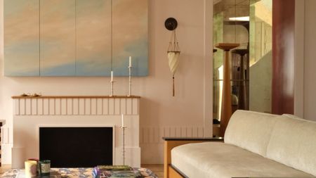 a room with modern furniture, a painted cloud artwork, and wall sconce with a tassel