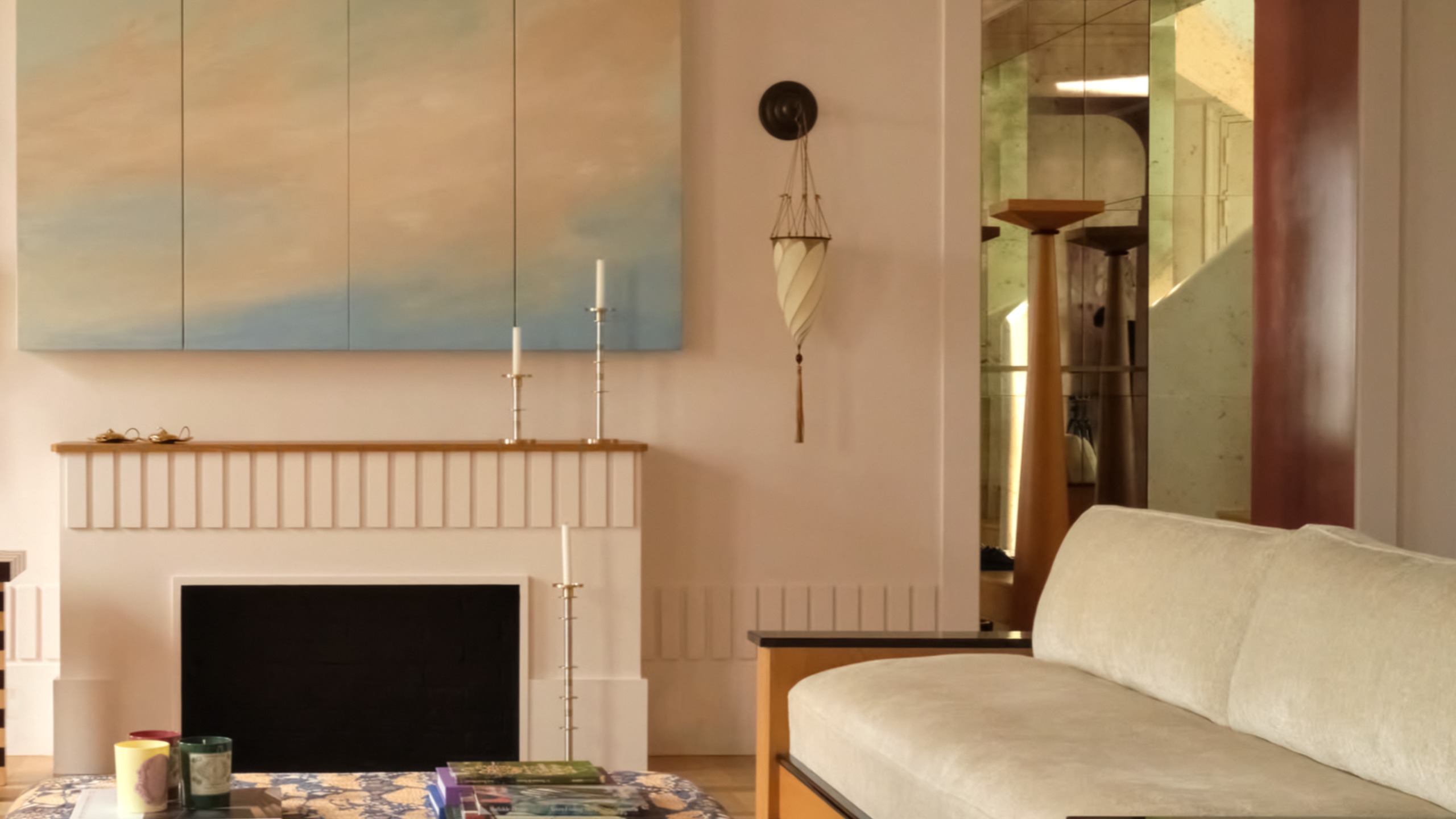 a room with modern furniture, a painted cloud artwork, and wall sconce with a tassel