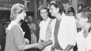 (Original Caption) 7/20/1983-London: Princess Diana of Wales shakes hands with John Taylor of the Duran Duran pop group 7/20, as lead singer Simon Le Bon (C) and fellow group member Andy Taylor (R) look on, at the Dominion Theatre, London where the Prince and Princess of Wales attended the Prince's Trust Rock Gala.