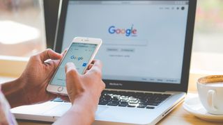Person använder Google på telefon och laptop