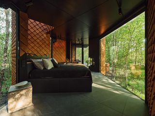 Cabin bedroom with bed facing huge window with view of woods