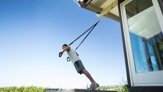 Man using the TRX Home2 suspension trainer for an outdoors workout