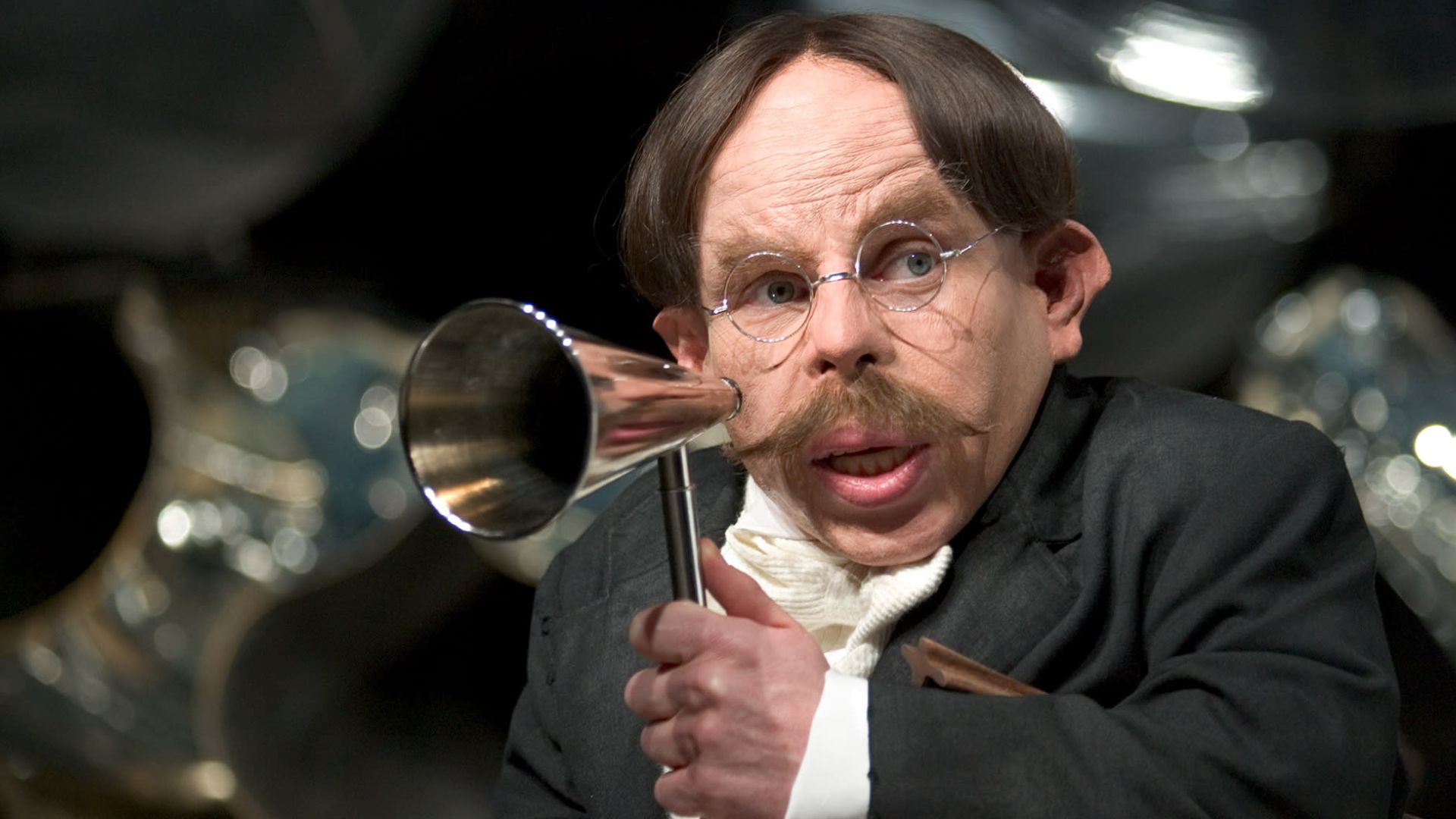 Professor Flitwick holds a speaker up to his mouth