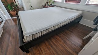 Side angle view of a queen Essentia Stratami organic mattress on a brown bed frame in our tester's bedroom