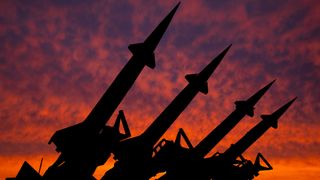 Missiles pointed at sunset sky