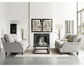 A pair of classically styled neutrally-upholstered sofas with wooden feet facing each other across a white living room