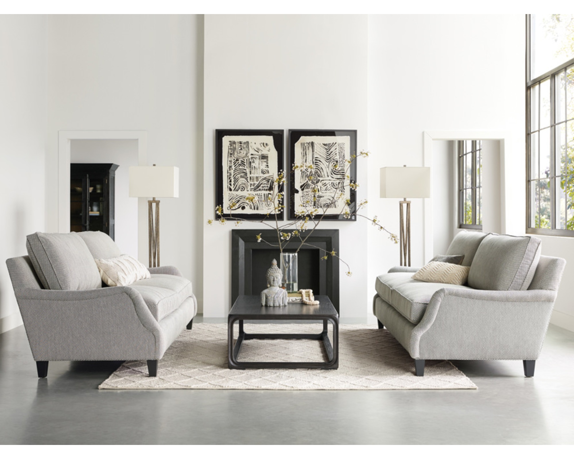 A pair of classically styled neutrally-upholstered sofas with wooden feet facing each other across a white living room