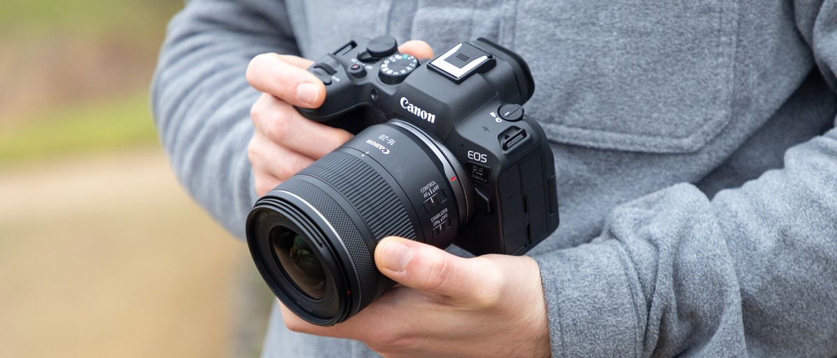 A man holding a Canon RF 16-28mm F2.8 IS STM attached to a Canon EOS R6 Mark II