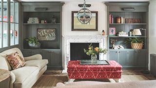 Modern living room with blue alcove shelving, red ottoman, cream sofa