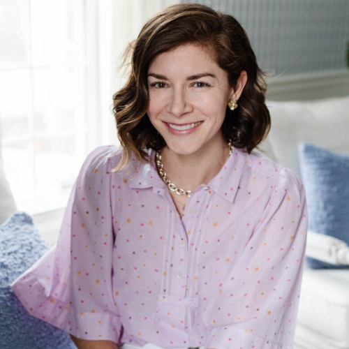 Image of a woman in a lilac blouse sitting in a white and blue room.
