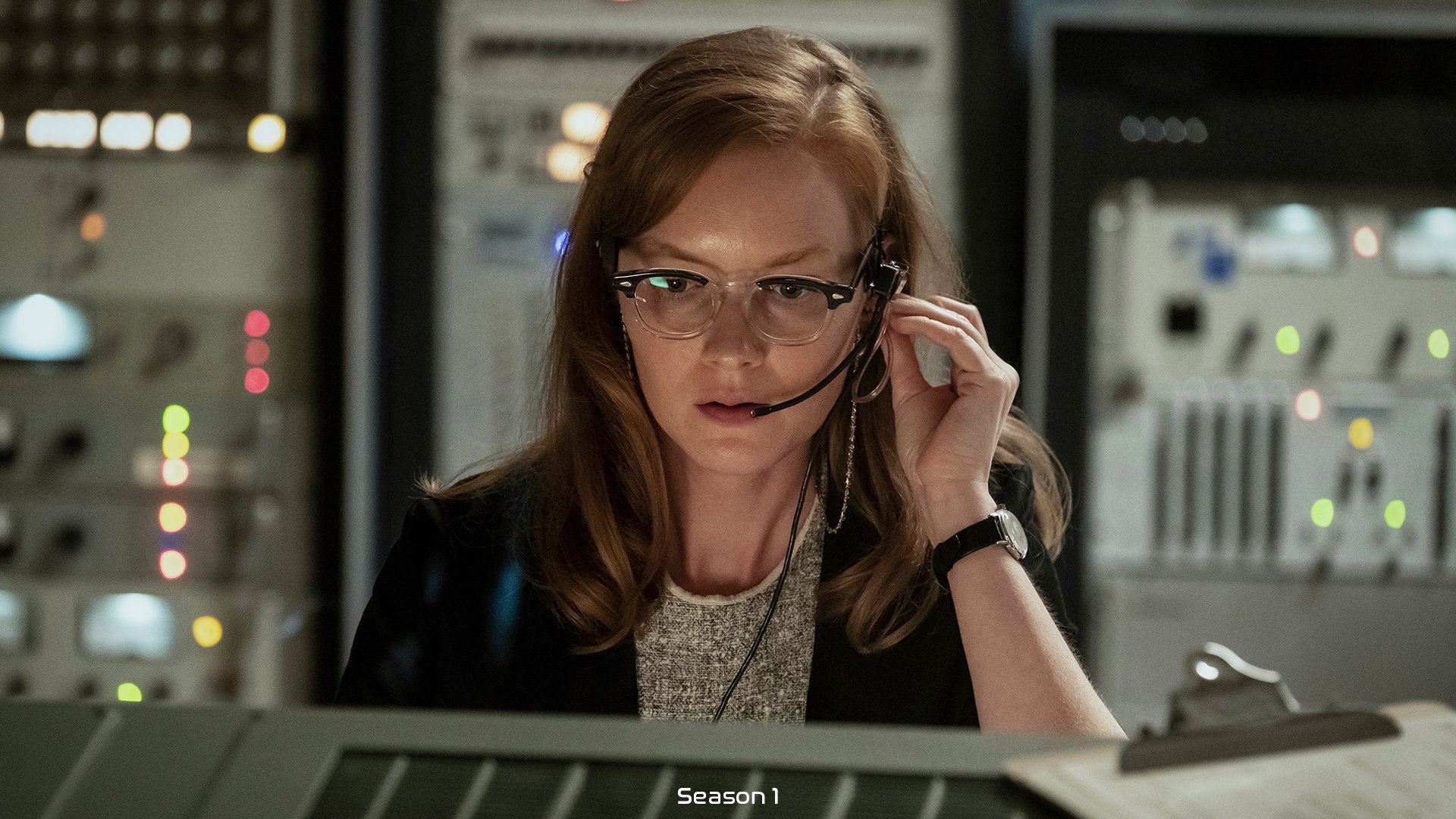 Uma mulher usando fones de ouvido monitorando uma missão espacial