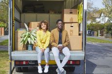 Young couple sitting on the back of a moving truck