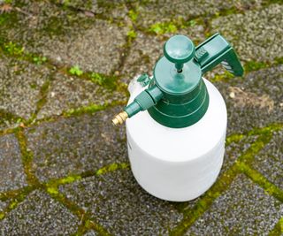 Plastic spray bottle filled with weed killer sitting on paving slabs