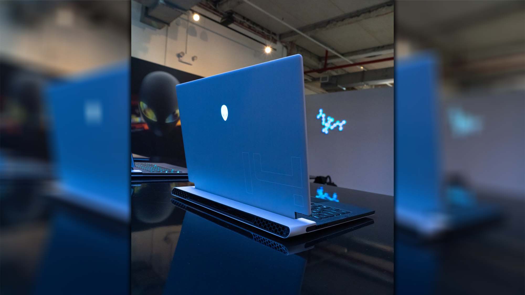 An Alienware gaming laptop on a table in a darkened room