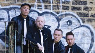 Eureka Machines standing on some iron steps in front of a brick wall