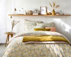 natural home accessories on a wall shelf above a bed with ditsy floral bedding - La Redoute