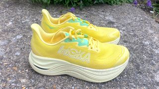 the Hoka Skyward X on a sidewalk in front of some flowers