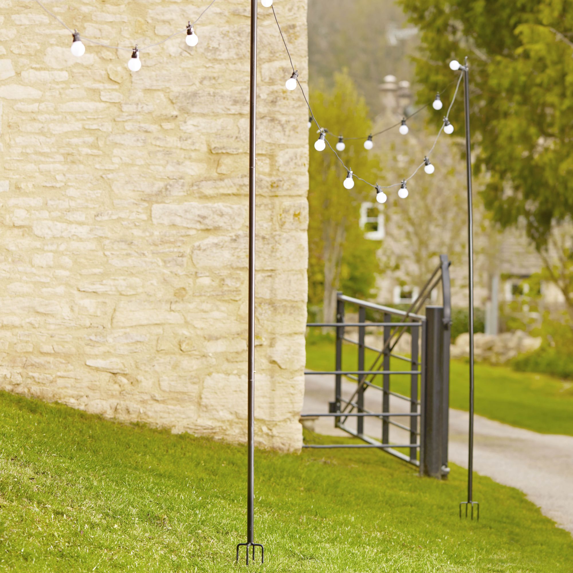 festoon lights being propped up by rakes in grass