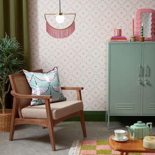 Light pink patterned wallpaper in living room, armchair and teal cabinets