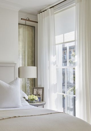 white bedroom with light and airy feel, white curtains, cream throw on bed, small bedroom