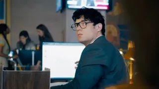 david corenswet in little glasses and a blue suit at a computer as the new clark kent in a still from superman 2025