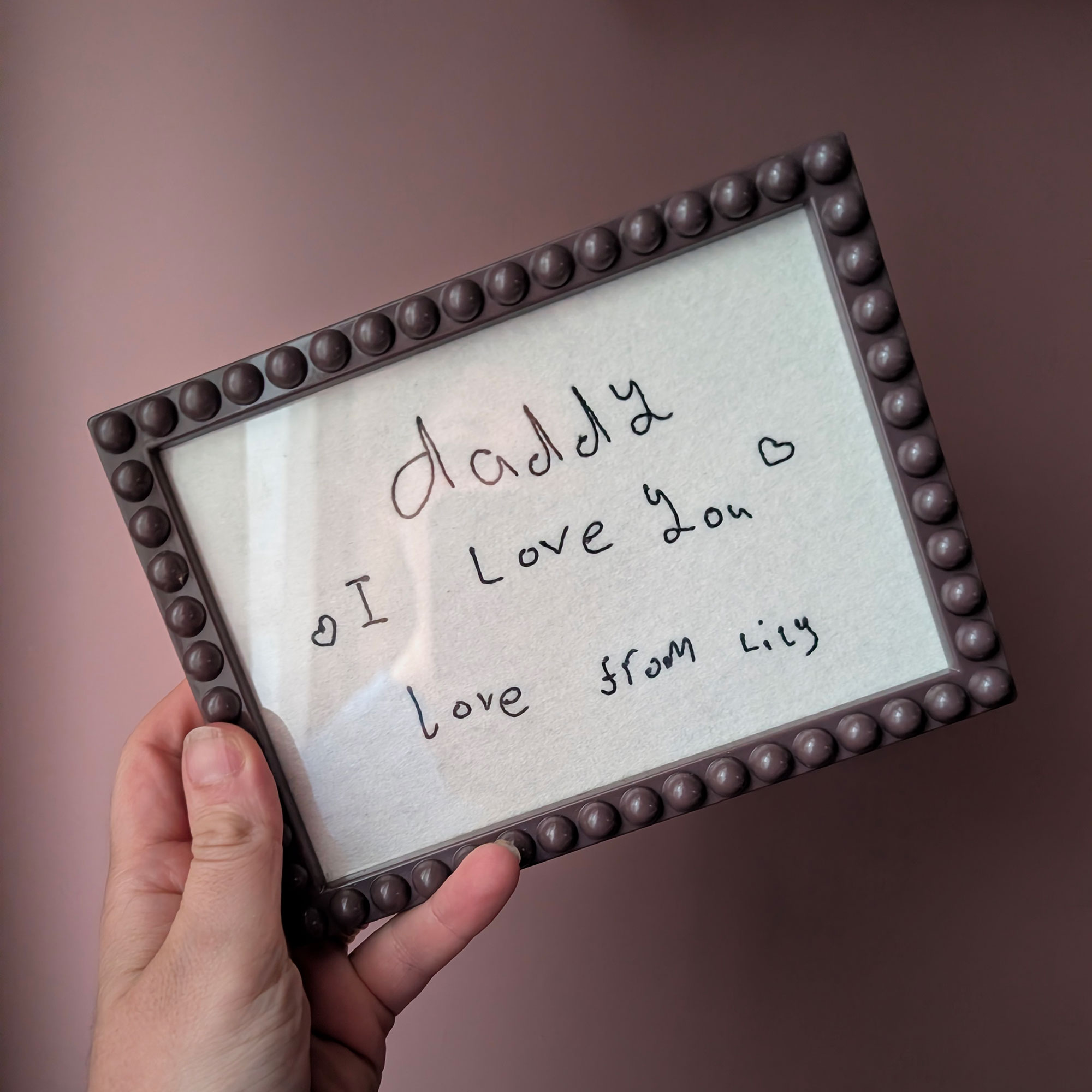 Person holding framed linen with embroidered writing
