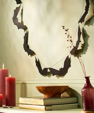 bat garland on neutral wall with red candles and stack of books