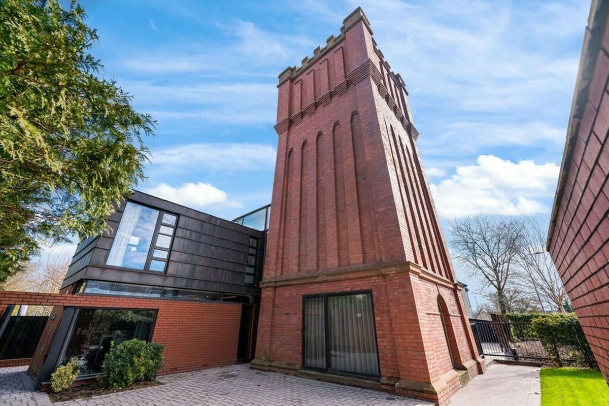 Ground floor view of the water tower&#039;s structure with traditional red brick walls and driveway