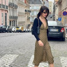 fashion influencer Tamara Mory wearing a green, polkadot dress on a cobblestone European street 