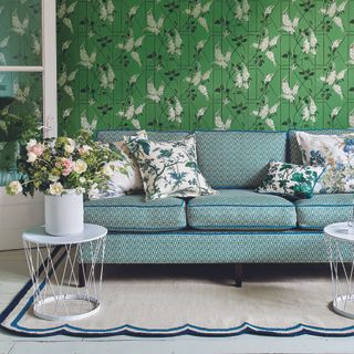 Living room with green wallpaper, grey sofa and scalloped rug.