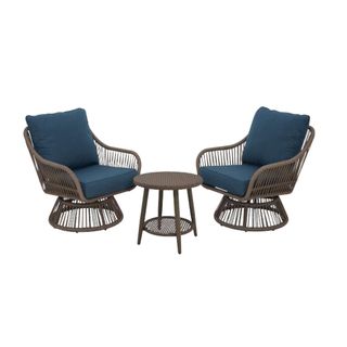 Two chairs and a small end table for a wicker patio set with blue cushions