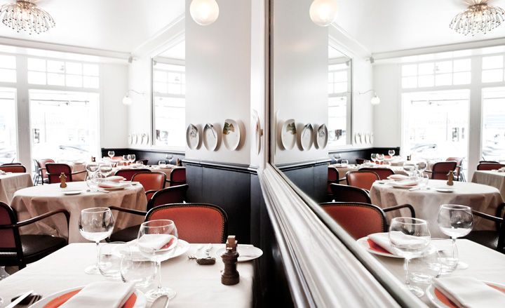 Red chairs with table cloth covered tables, dark wood bordered walls with white paint finish