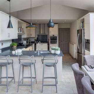 cream kitchen with grey worktops bar stools and pendant lamps