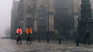 Two riders cycle in the mist in Edinburgh