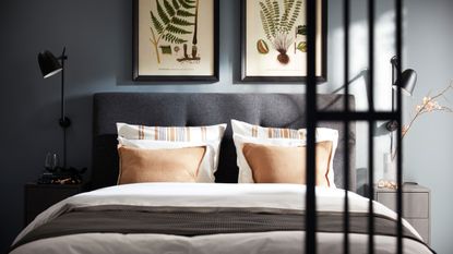 IKEA blue bedroom with grey double bed with white bedding and botanical prints above in black frames