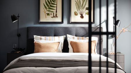 IKEA blue bedroom with grey double bed with white bedding and botanical prints above in black frames
