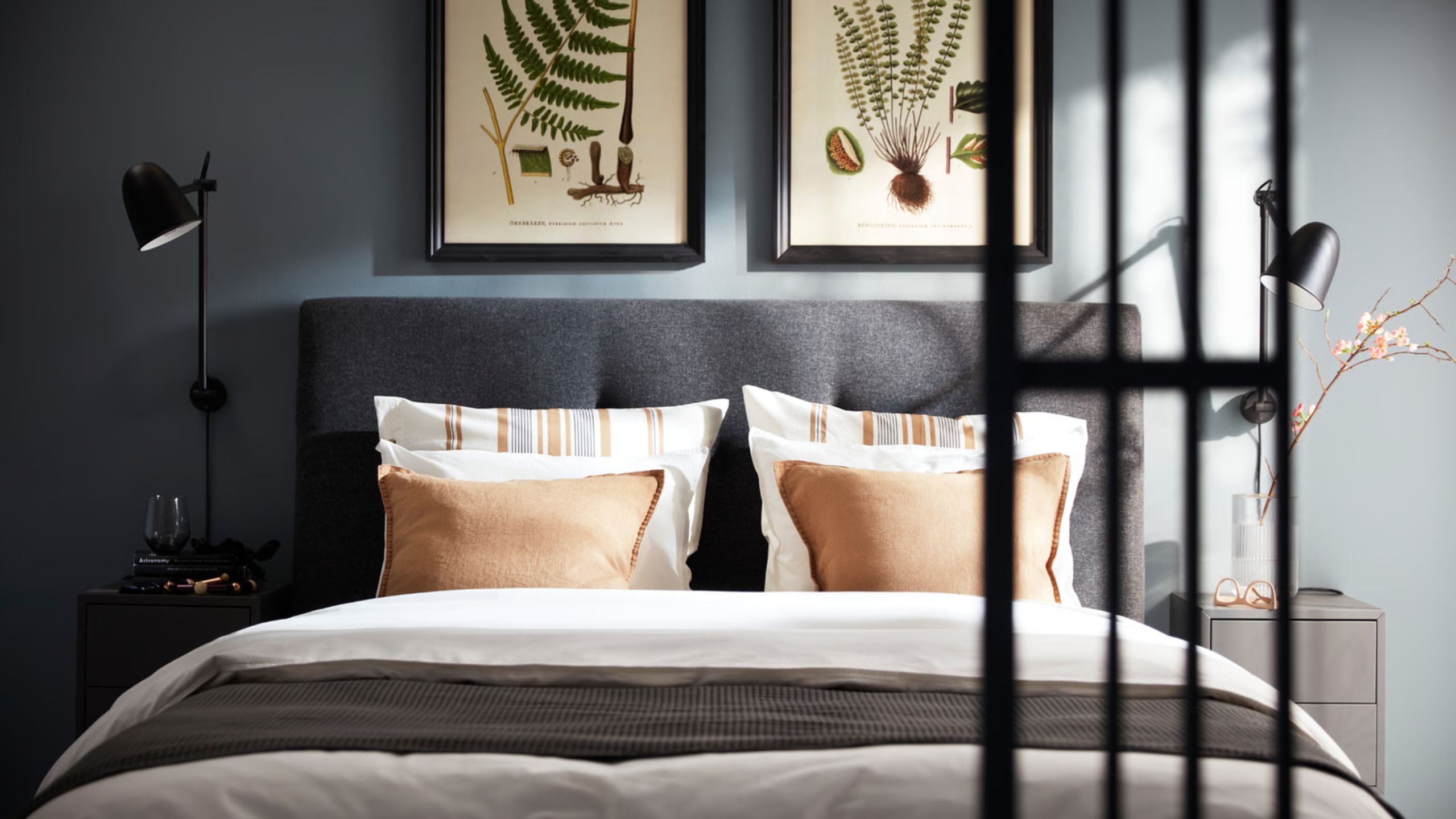 IKEA blue bedroom with grey double bed with white bedding and botanical prints above in black frames