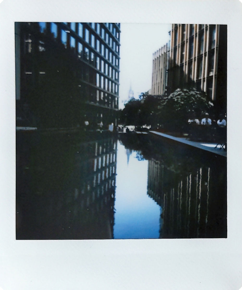 Digitized instant photo taken with the Fujifilm Instax SQ40 of highrise buildings reflected in water