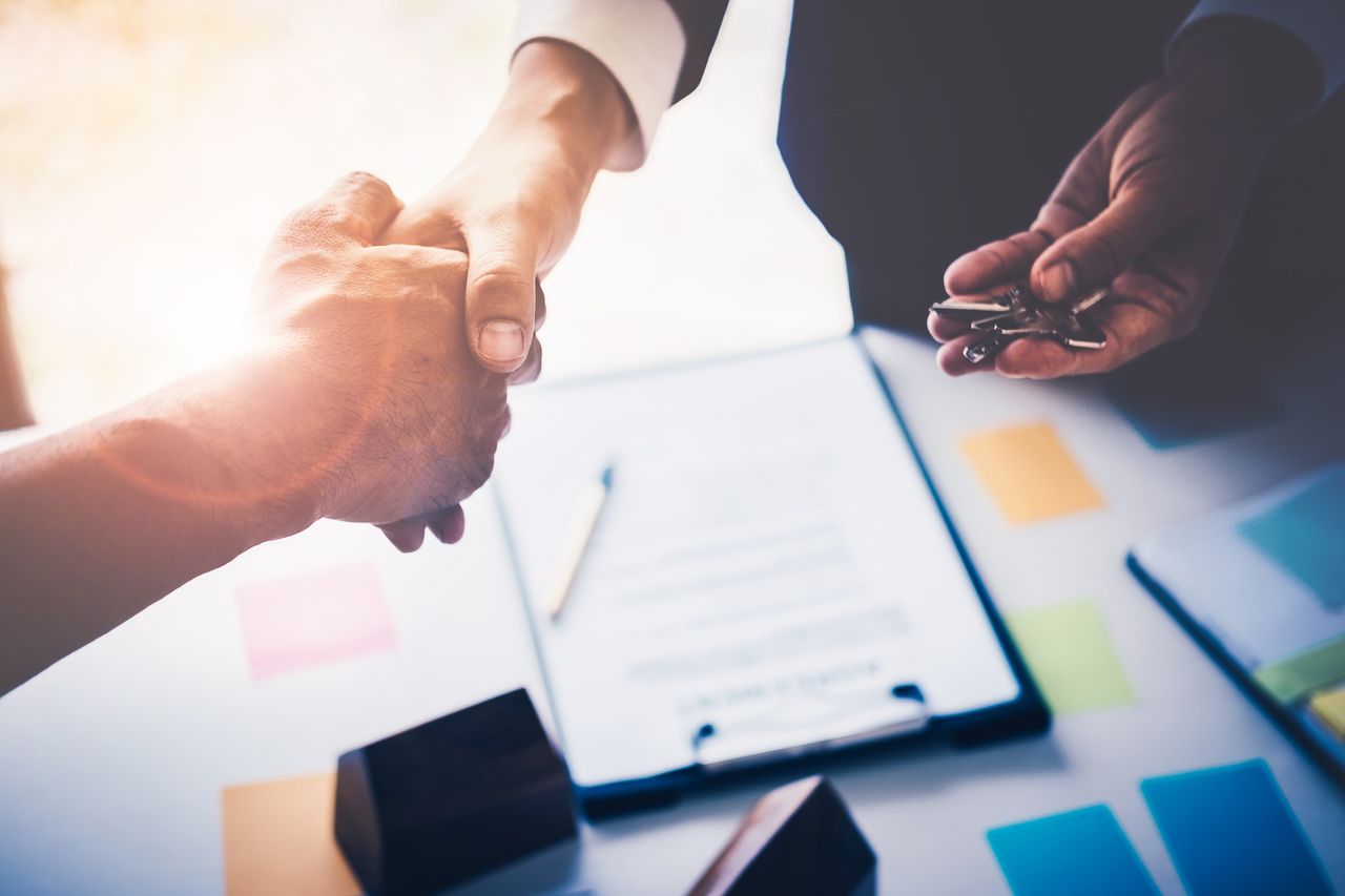 A real estate agent and a home buyer shaking hands.